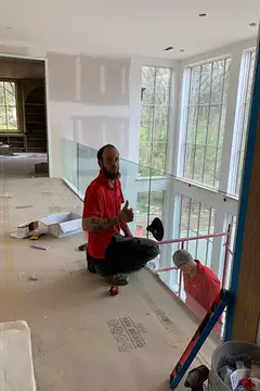 A service professional from Glass Doctor of Nashville installing a glass railing on a walkway.