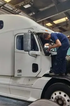 A Glass Doctor Auto of Southampton service professional working on a windshield replacement for a white semi truck in the shop.