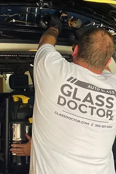 A Glass Doctor Auto of Castle Rock in a white shirt working on replacing the glass on the back hatch of an SUV.