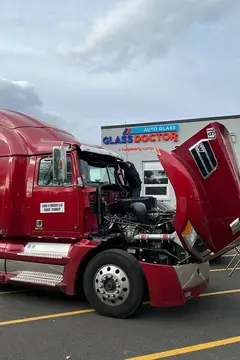 A red semi truck receiving a windshield repair service by a Glass Doctor Auto of Southampton service professional.
