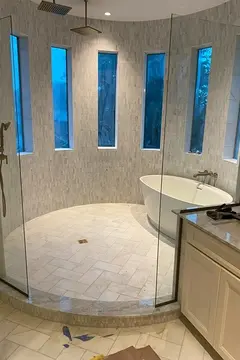 A round shower enclosure with a tub and tall narrow windows and glass splash panels from Glass Doctor of Nashville.