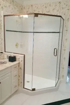 Three-panel semi-frameless shower enclosure with diagonal panel and swinging door and white tiles.