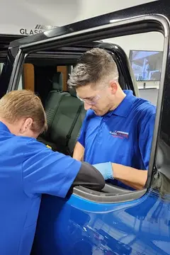 Two service professionals from Glass Doctor Auto of Cedar Park work together to replace a rear door window on a pickup truck.