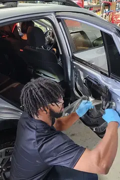 A service professional from Glass Doctor Auto of Cedar Park works to replace a rear door window on a car.