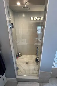 A walk-in shower with grey tiles and a single swinging frameless glass door installed by Glass Doctor of York Region.