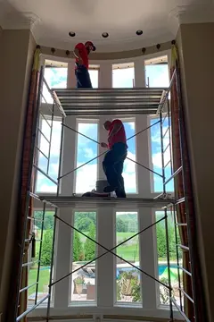 Professional window installers from Glass Doctor of Nashville installing glass in a tall bay window.