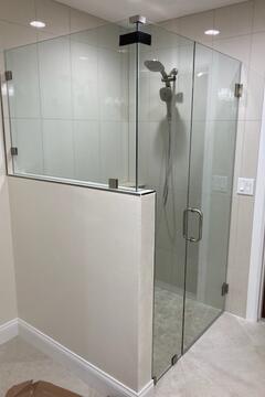 A frameless glass shower enclosure with a half-wall and three panes of glass by Glass Doctor of Sarasota.