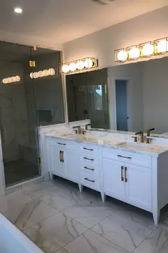 Tinted frameless glass panel and door installed by Glass Doctor of York Region and separating a shower from a double sink vanity and mirror.
