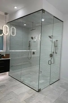 Frameless clear glass panels enclosing a shower with textured white walls installed by Glass Doctor of Nashville.