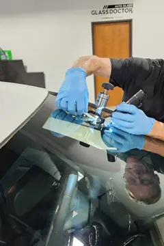 A Glass Doctor Auto of Cedar Park service professional uses to tool in the process of a windshield chip repair job.