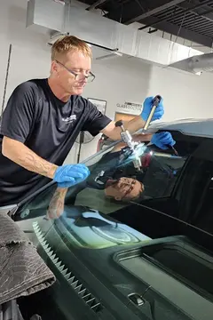 A Glass Doctor Auto of Cedar Park service professional works on repairing a rock chip in a windshield using a specialized tool.