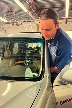 A Glass Doctor Auto of Castle Rock service professional using a tool to remove the windshield of a silver vehicle.