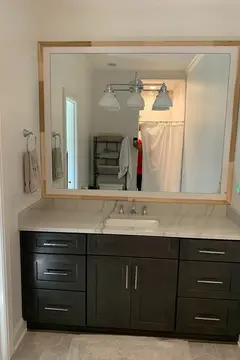 Mirror with wood frame mounted over a vanity with marble countertop from Glass Doctor of Nashville.