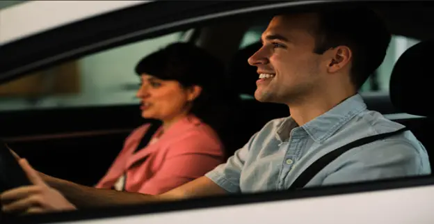 A woman and man sitting inside of a white car.