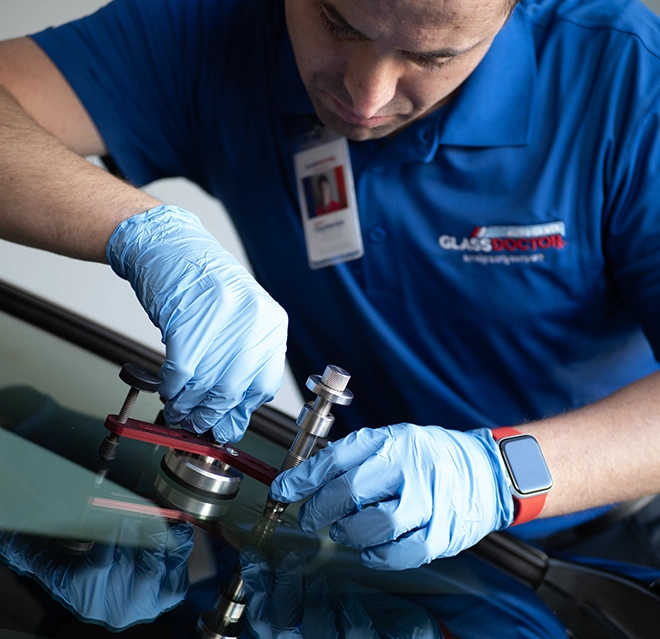 Glass Doctor professional working on car windshield with a tool.