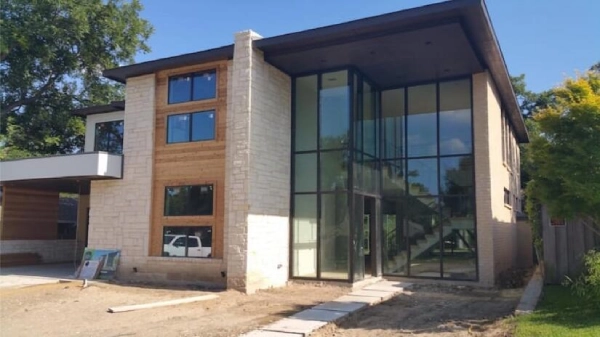 A modern home with a twenty foot tall exterior wall made of glass