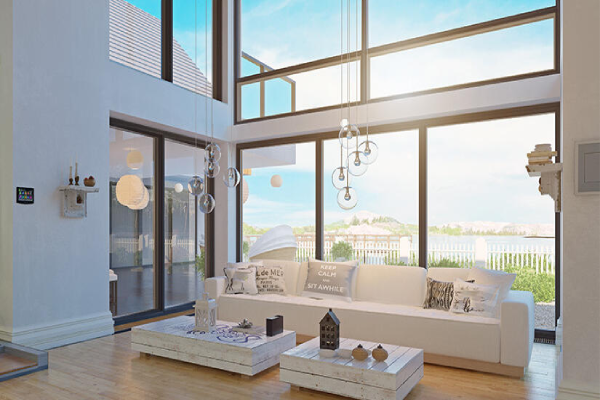 A bright living room featuring large windows and a modern white couch, creating an airy and inviting atmosphere.