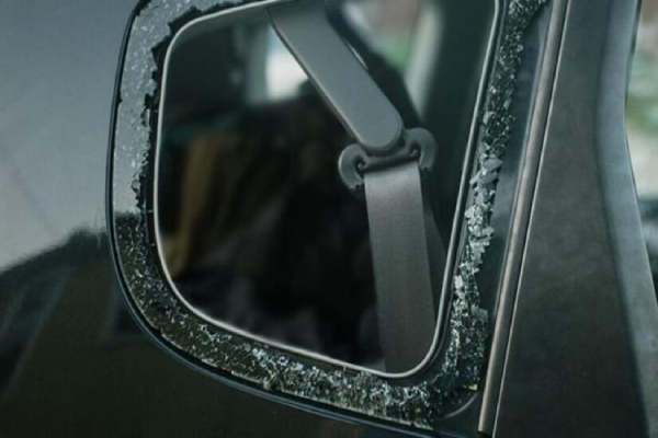 A car side mirror with a shattered glass mirror.