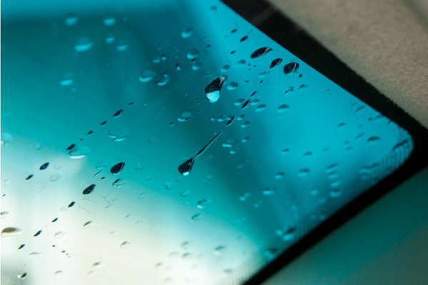 A close-up of a car window covered in raindrops.