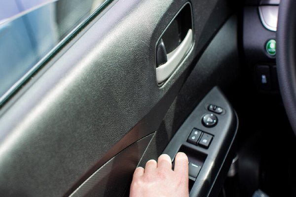 A close-up of a hand on a car's steering wheel, showing the driver's control.