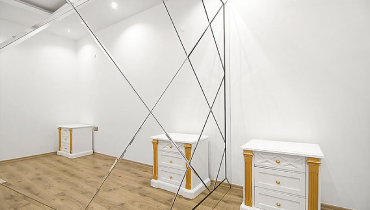 A mirror reflects a room furnished in white, showcasing a bright and airy atmosphere.