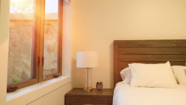 A neatly made bed with white sheets and a bedside lamp illuminating the space.