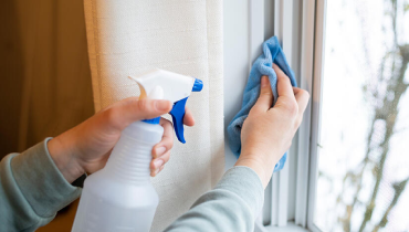 A person using a window cleaner to wipe a glass window, ensuring it is clean and streak-free.