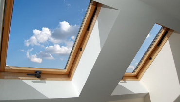 Bright blue sky with fluffy white clouds visible through a skylight.