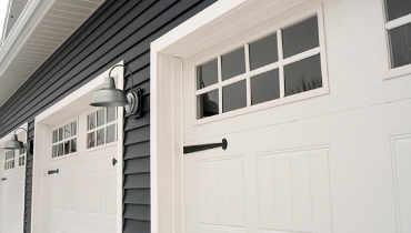 Garage doors with windows and side lights, enhancing the exterior of a house.