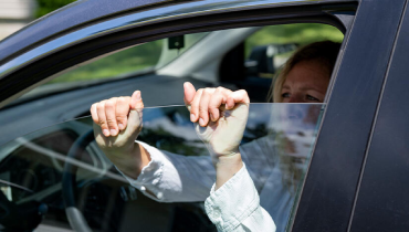 A woman holds up a window, displaying her hand in front of it.