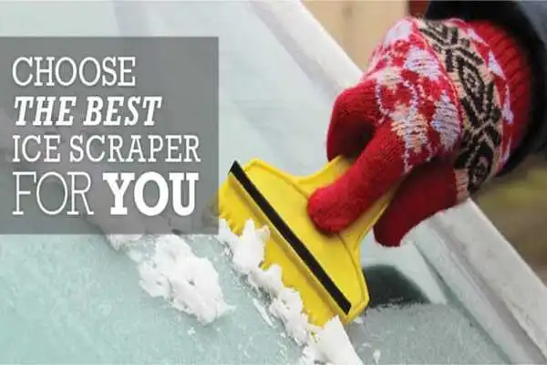 A hand with wool gloves scraping the ice off a windshield with a yellow ice scraper