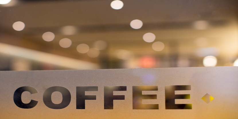 Clearly etched "Coffee" on glass window with shop, cafe, restaurant lighting in background.