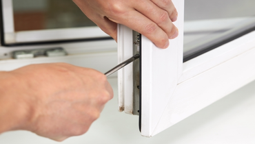 Handyman adjusting window indoors.