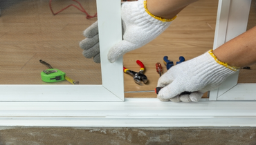 Worker adjusting sliding glass door with a screwdriver